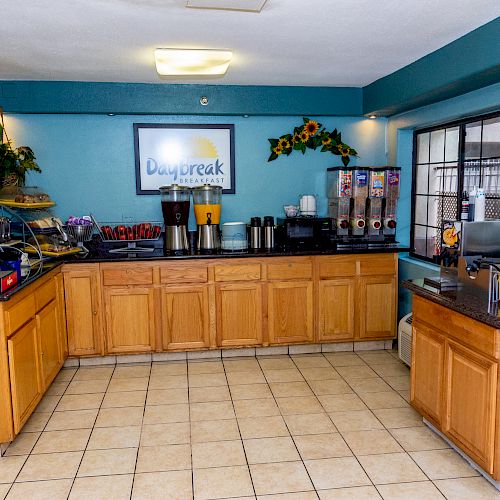 A breakfast station with various food and drink options, including coffee makers, cereal dispensers, waffle maker, and a sign reading 