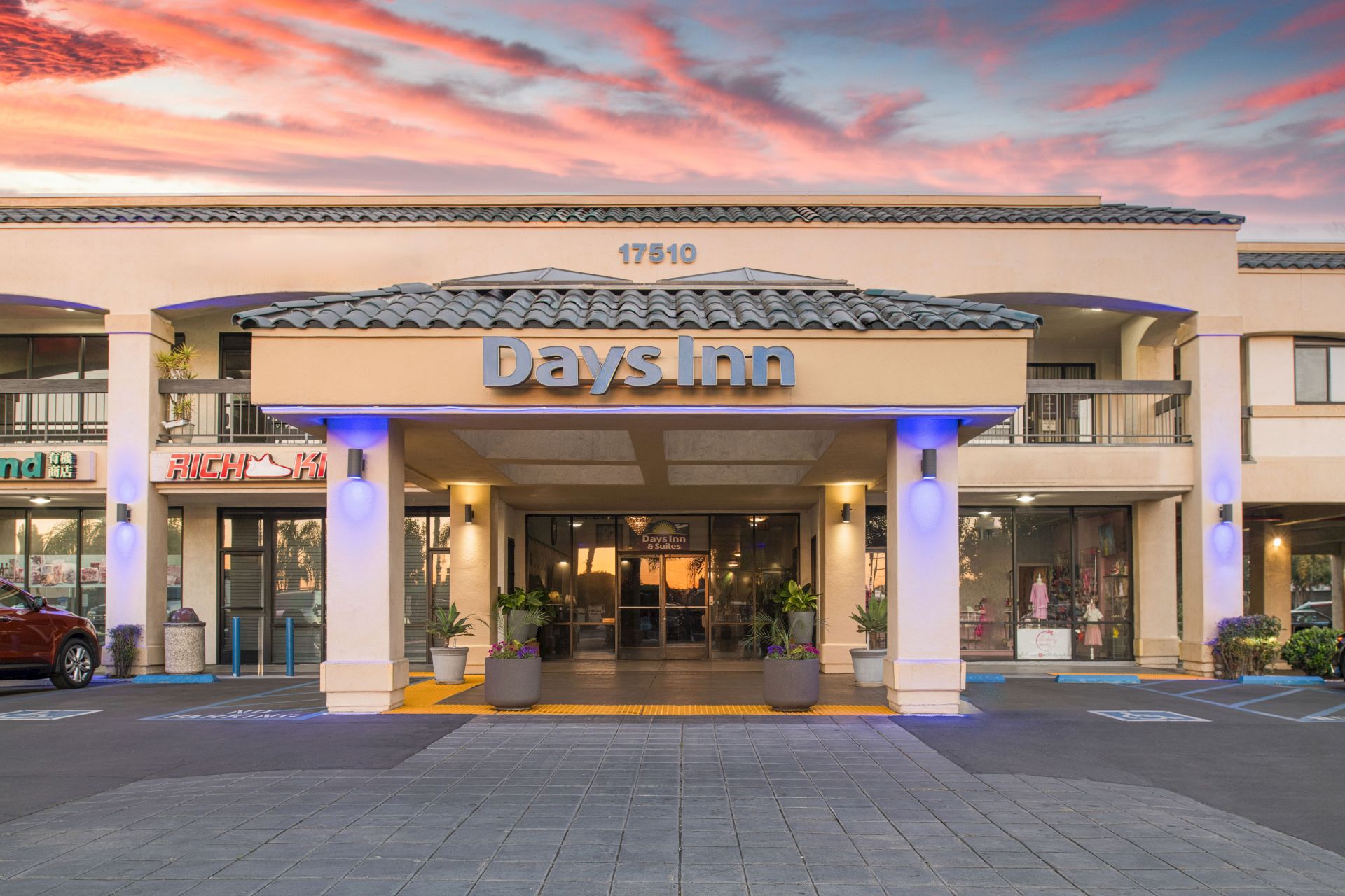 The image shows the front entrance of a Days Inn hotel with a sunset sky in the background.