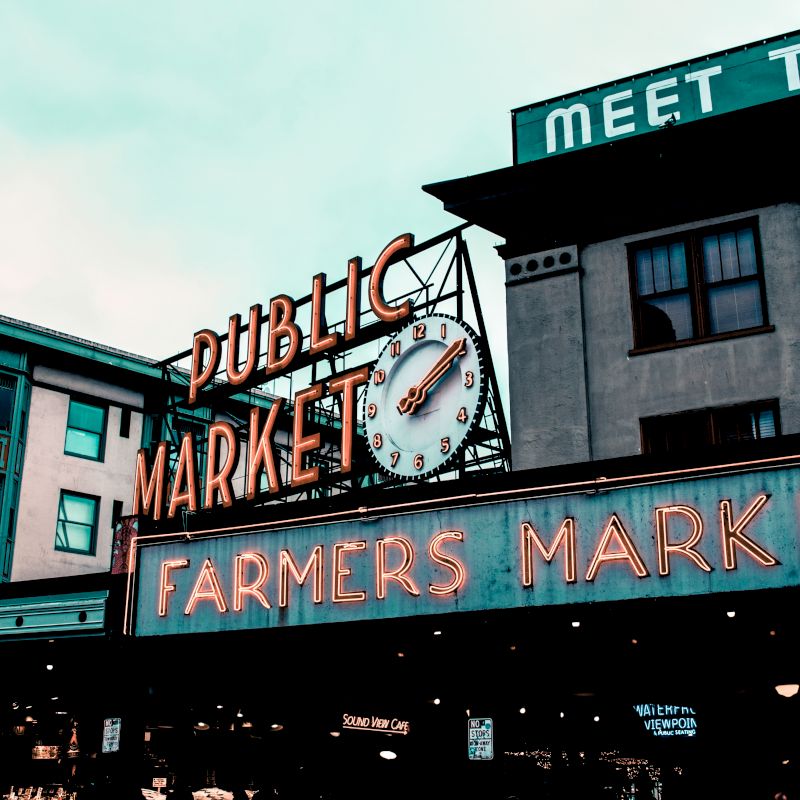 The image shows the iconic signage for a "Public Market" and "Farmers Market" with a large clock, likely representing a famous location.