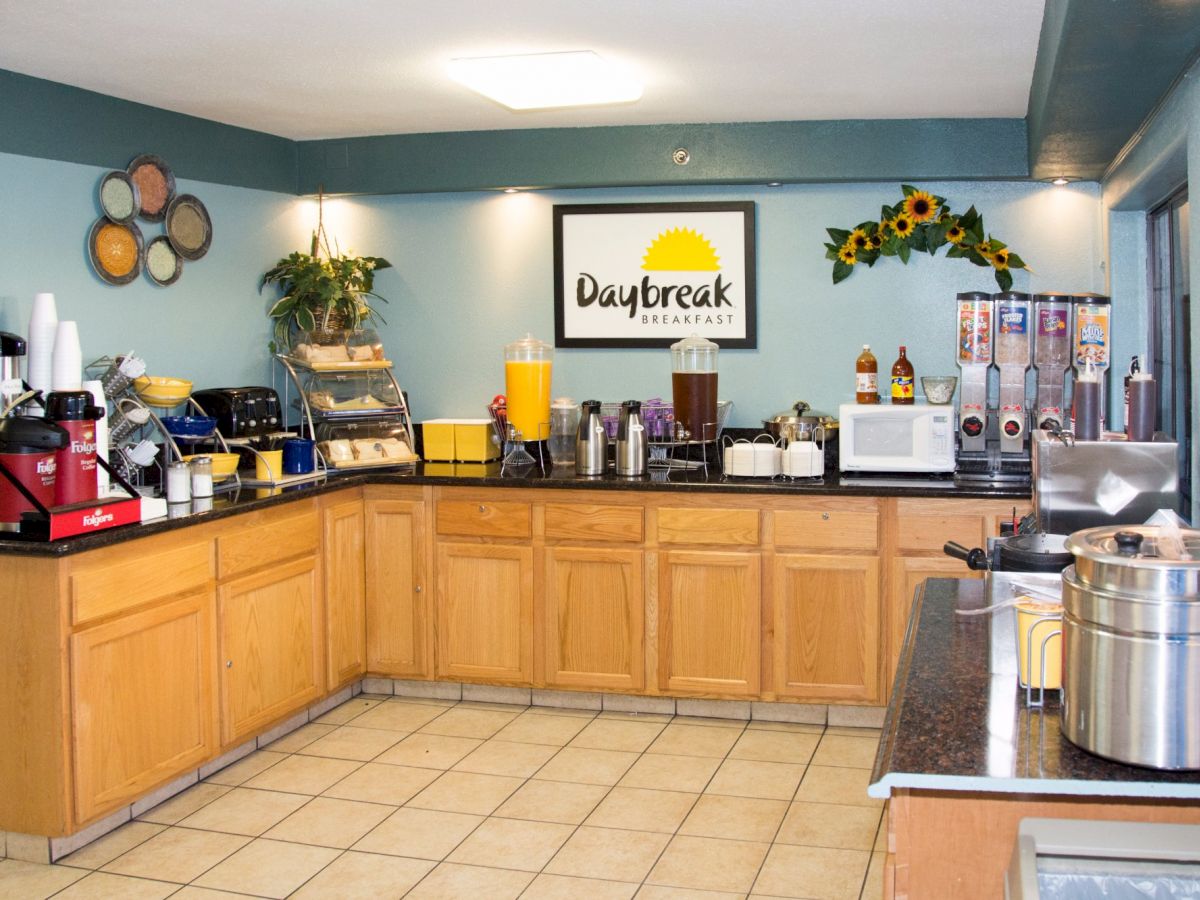 This image shows a breakfast buffet area with various appliances, beverages, and food options, labeled 